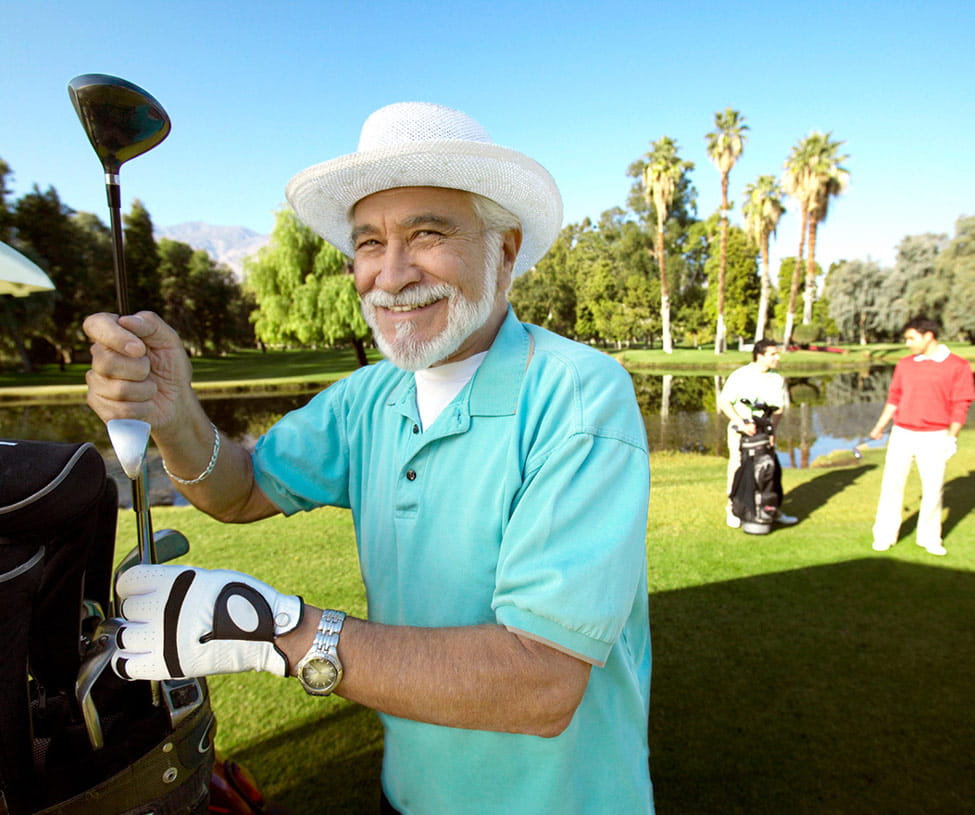 A gentleman pulls a golf club from his bag.