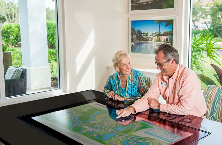 A sales team member shows a woman a digital map.